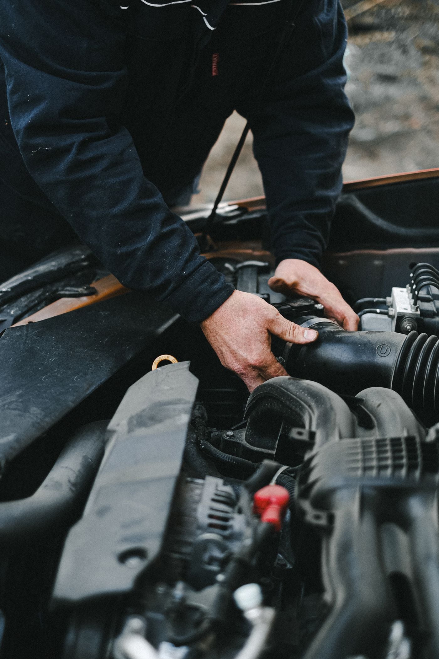 Auto mechanic working carefully beneath the hood of a car